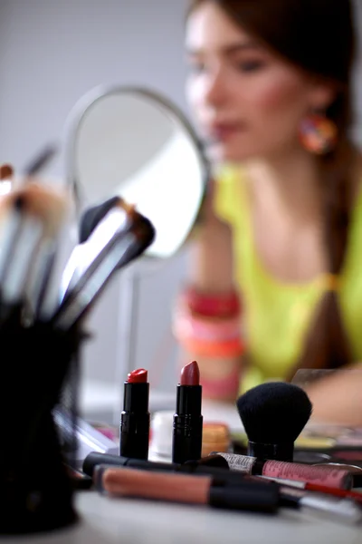 Молода красива жінка робить макіяж біля дзеркала, сидить за столом — стокове фото