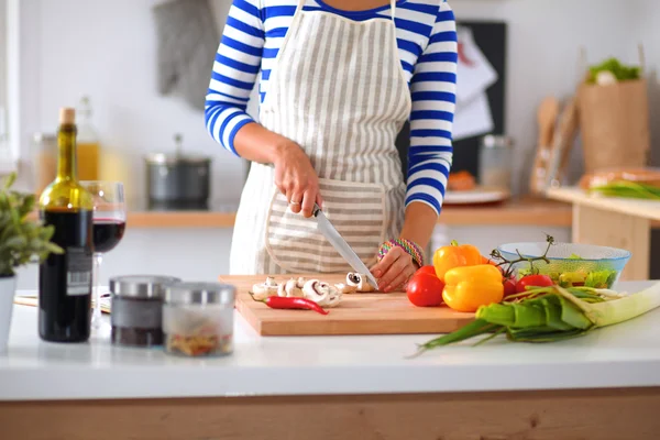 Jeune femme coupant des légumes dans la cuisine — Photo