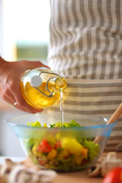 Jovem mulher misturando salada fresca de pé perto da mesa — Fotografia de Stock