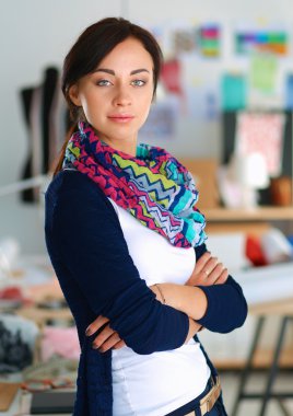 Güzel moda tasarımcısı stüdyoda duruyor.