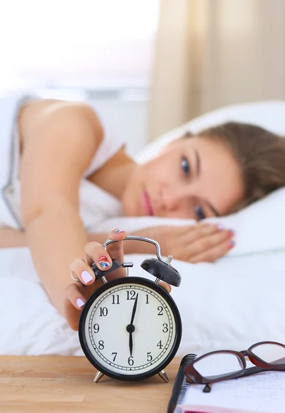 Una mujer joven apagando su despertador por la mañana — Foto de Stock