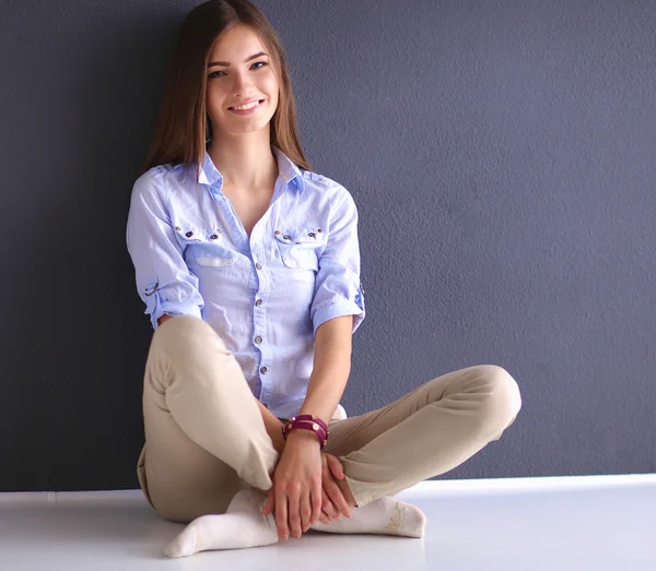 Mujer joven sentada en el suelo cerca de la pared oscura — Foto de Stock