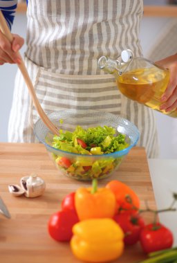Masanın yanında duran taze salatayı karıştıran genç kadın.