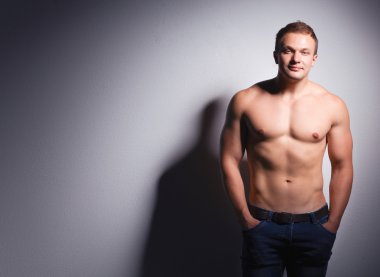 Karanlık bir arka plan üzerinde ayakta sağlıklı kas genç adam