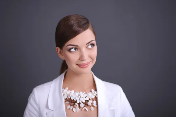 Portret van een jonge vrouw met parels, staande op een grijze achtergrond — Stockfoto