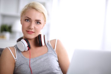Evdeki genç ve güzel kadın kanepede oturup müzik dinliyor.
