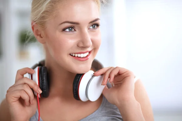 Jeune belle femme à la maison assise sur un canapé et écoutant de la musique — Photo