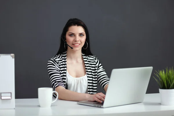 Beautiful business woman working at her desk with headset and laptop — Stock Photo, Image