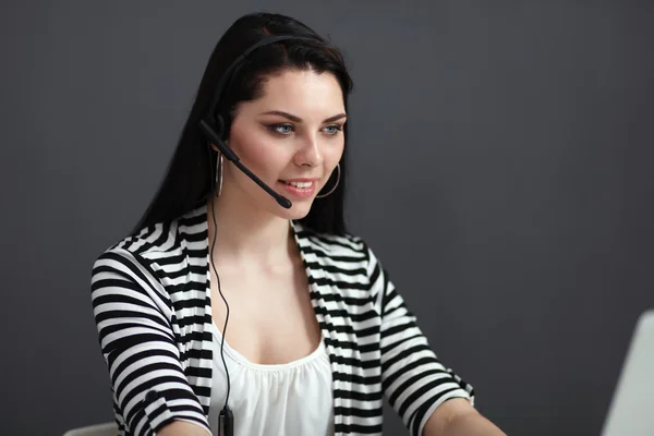 Hermosa mujer de negocios que trabaja en su escritorio con auriculares y portátil — Foto de Stock