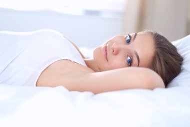 Yatakta rahat ve mutlu bir şekilde yatan güzel bir genç kadın.
