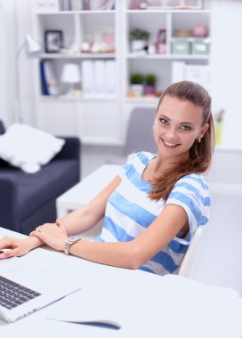 Elinde evrakları olan kadın masanın üstünde oturuyor.