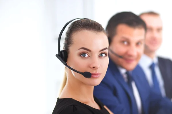 Retrato de mujer de negocios hermosa en auriculares sonriendo con colegas de fondo — Foto de Stock