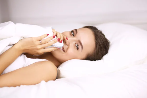 Uma jovem mulher bonita espreitando debaixo das capas em seu quarto feliz — Fotografia de Stock