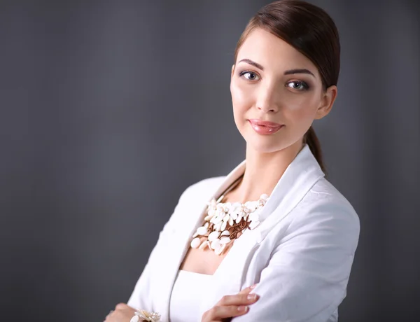 Portret van een jonge vrouw met parels, staande op een grijze achtergrond — Stockfoto