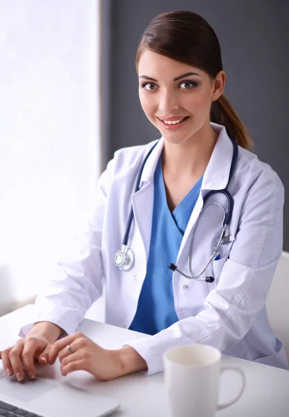 Médico feminino trabalhando sentado em fundo cinza — Fotografia de Stock