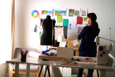 Güzel moda tasarımcısı stüdyoda duruyor.