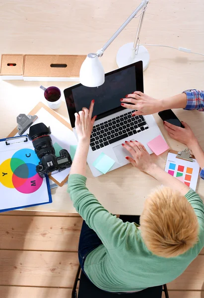 Vrouwelijke fotograaf zittend op het bureau met laptop — Stockfoto