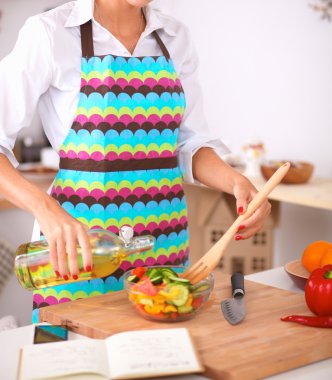 Masanın yanında duran taze salatayı karıştıran genç kadın.