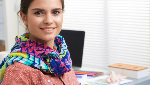 Smiling female fashion designer sitting at office desk — Stock Photo, Image