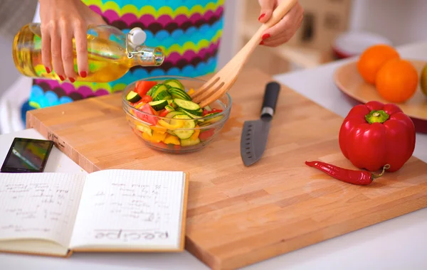 Jovem mulher misturando salada fresca de pé perto da mesa — Fotografia de Stock