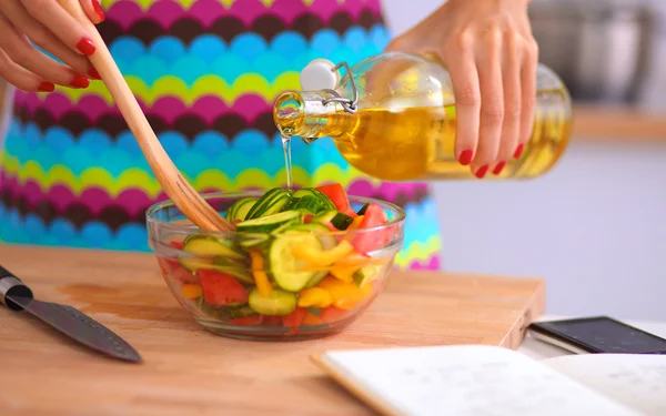 Jonge vrouw mengen verse salade staan in de buurt van bureau — Stockfoto