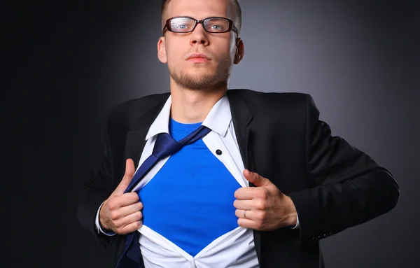 Joven hombre de negocios actuando como un súper héroe y rasgando su camisa, aislado sobre un fondo gris — Foto de Stock