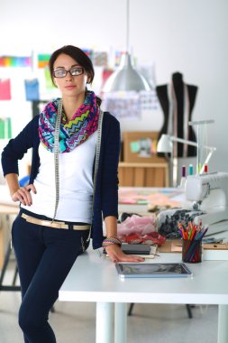 Güzel moda tasarımcısı stüdyoda duruyor.