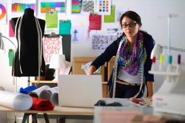 Güzel moda tasarımcısı stüdyoda duruyor.