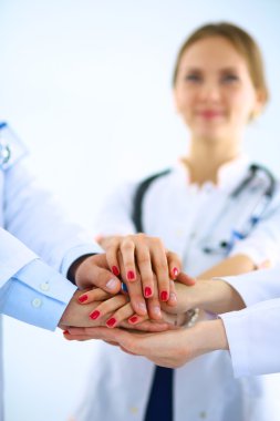 Doktorlar ve hemşireler tıbbi bir ekipte el ele tutuşuyorlar.