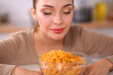 Gülümseyen çekici kadın mutfağın içinde kahvaltı yapıyor.