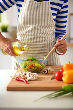 Masanın yanında duran taze salatayı karıştıran genç kadın.