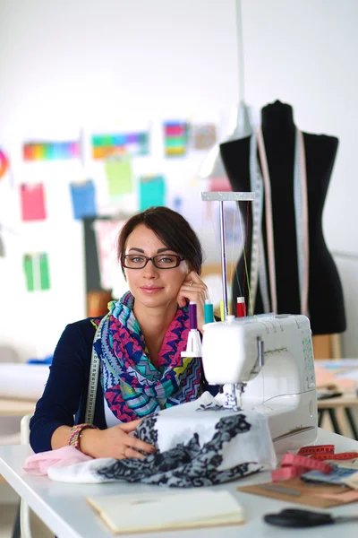 Mujer joven cosiendo sentado en su lugar de trabajo — Foto de Stock