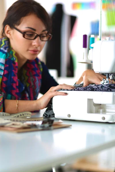 Mujer joven cosiendo sentado en su lugar de trabajo — Foto de Stock