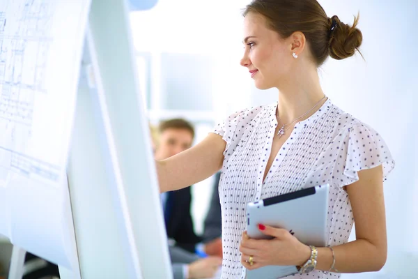 Femme d'affaires écrivant sur un tableau à feuilles mobiles tout en donnant une présentation à ses collègues au bureau — Photo