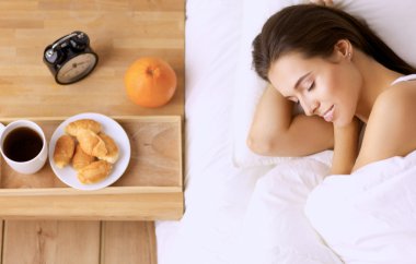 Genç ve güzel bir kadın yatakta yatıyor.