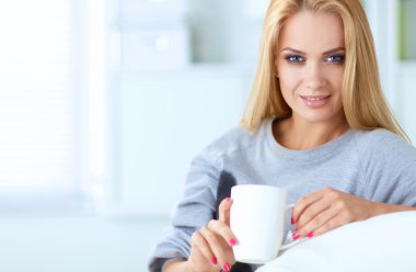 evde kanepenin üzerine bir fincan genç güzel kadın