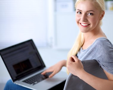 Genç ve güzel bir kadın evde dizüstü bilgisayar kullanıyor.