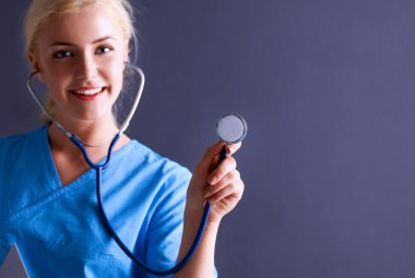 Steteskopla dinleyen kadın doktor, gri arka planda izole edilmiş.