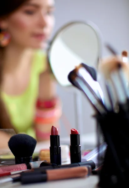 Jonge mooie vrouw maken make-up in de buurt van spiegel, zitten aan de balie — Stockfoto