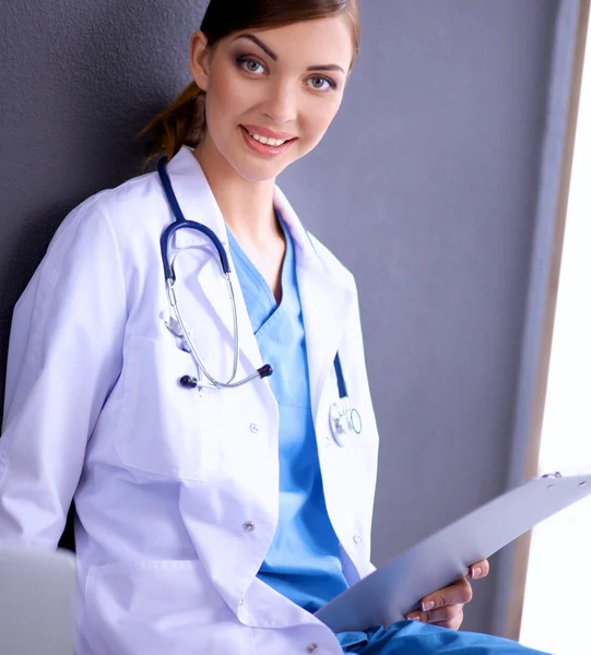 Vrouwelijke arts werken zitten op grijze achtergrond — Stockfoto