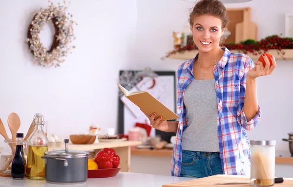 Ung kvinna läser kokbok i köket, letar efter recept — Stockfoto