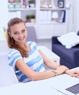 Elinde evrakları olan kadın masanın üstünde oturuyor.