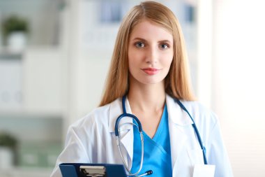 Hastane koridorunda klasörlü kadın doktor portresi.
