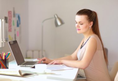 Masasında ve bilgisayarında evrakları olan bir kadın.