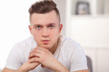 Genç adam sandalyede oturuyor.