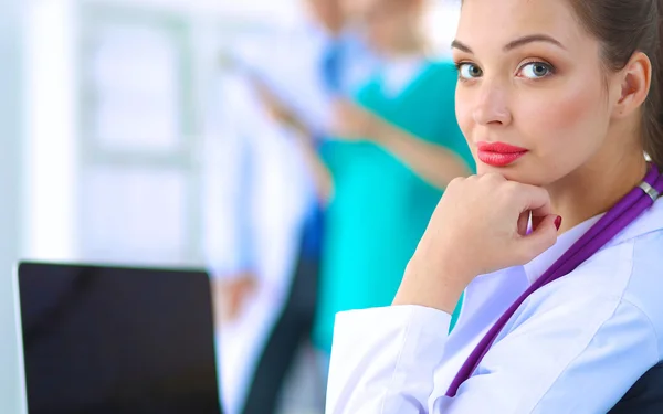 Hermosa joven sonriente doctora sentada en el escritorio — Foto de Stock