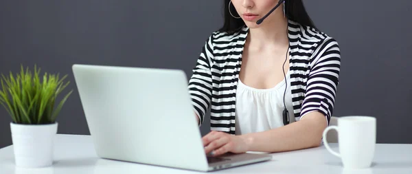 Hermosa mujer de negocios que trabaja en su escritorio con auriculares y portátil — Foto de Stock