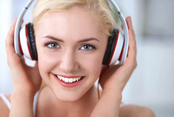 Young beautiful woman at home sitting on sofa and listening music — Stock Photo, Image