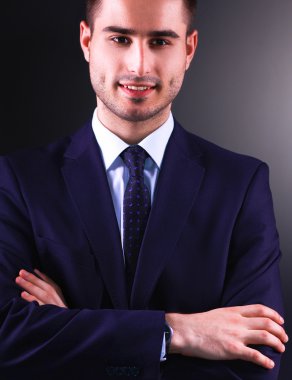 Gri arka plan üzerinde duran gülümseyen genç adam portresi