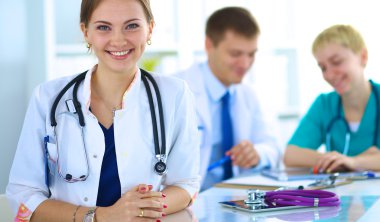 Masada oturan gülümseyen güzel genç bayan doktor.